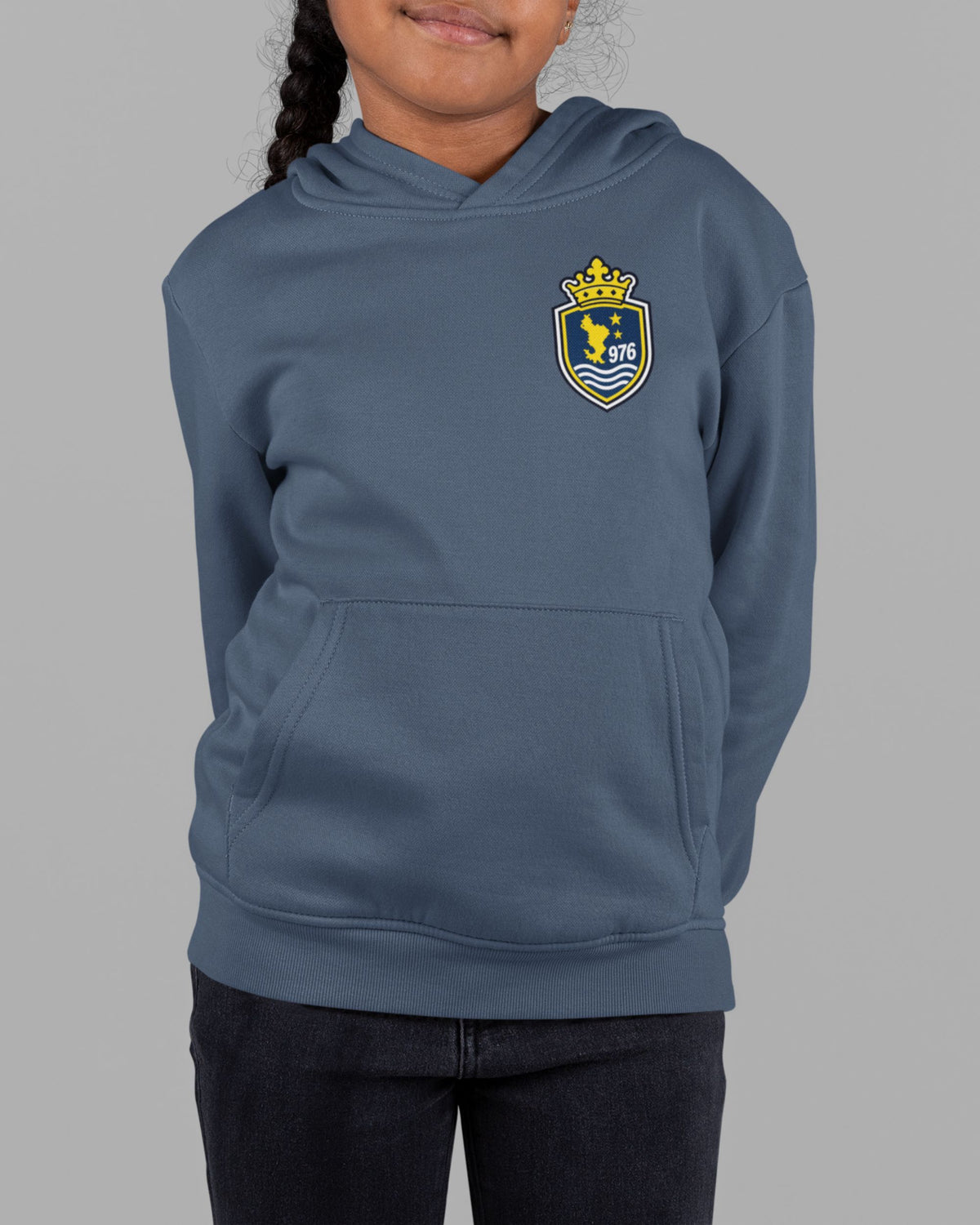 Enfant portant le sweat à capuche bleu marine WASI, avec écusson couronné 976 sur la poitrine et poche kangourou.
