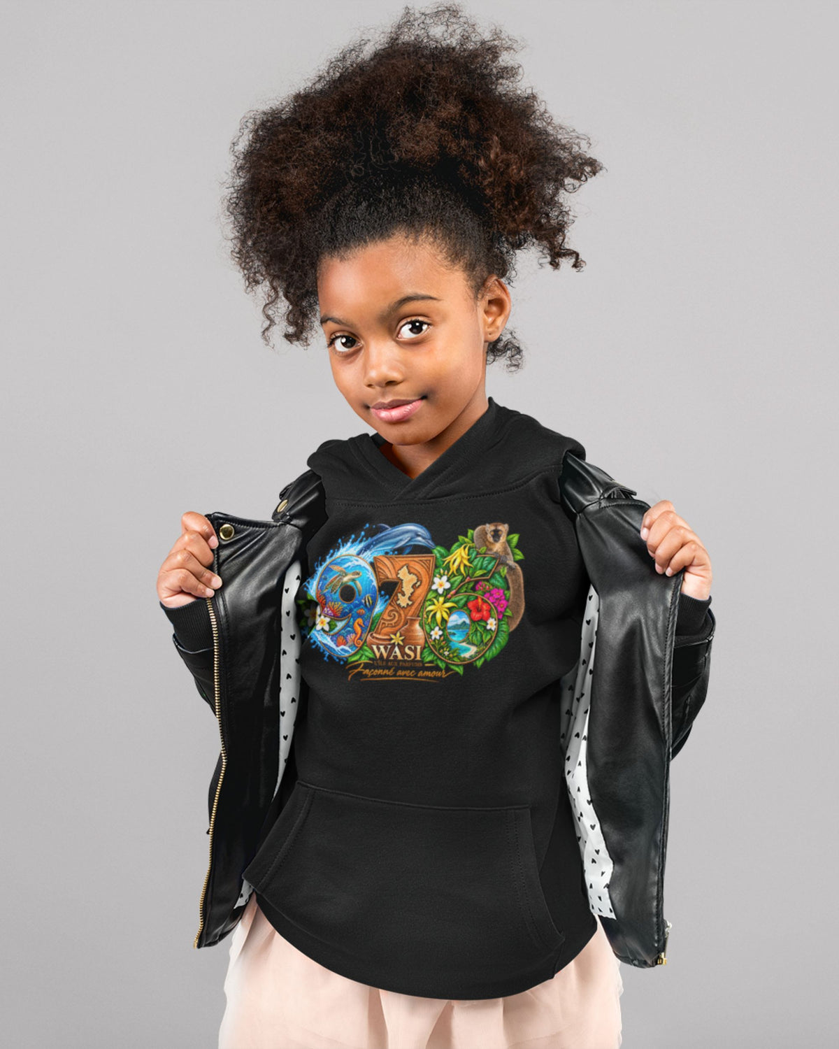 Enfant portant le sweat à capuche noir WASI, motif 976 coloré avec dauphin, maki et fleurs, sous une veste noire ouverte