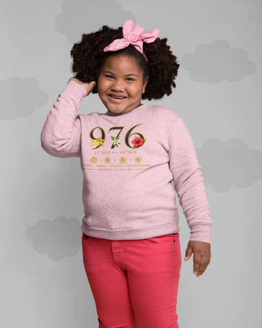 Enfant souriante portant le sweat rose clair au motif 976 fleuri, avec un nœud rose dans les cheveux et un pantalon rouge. 