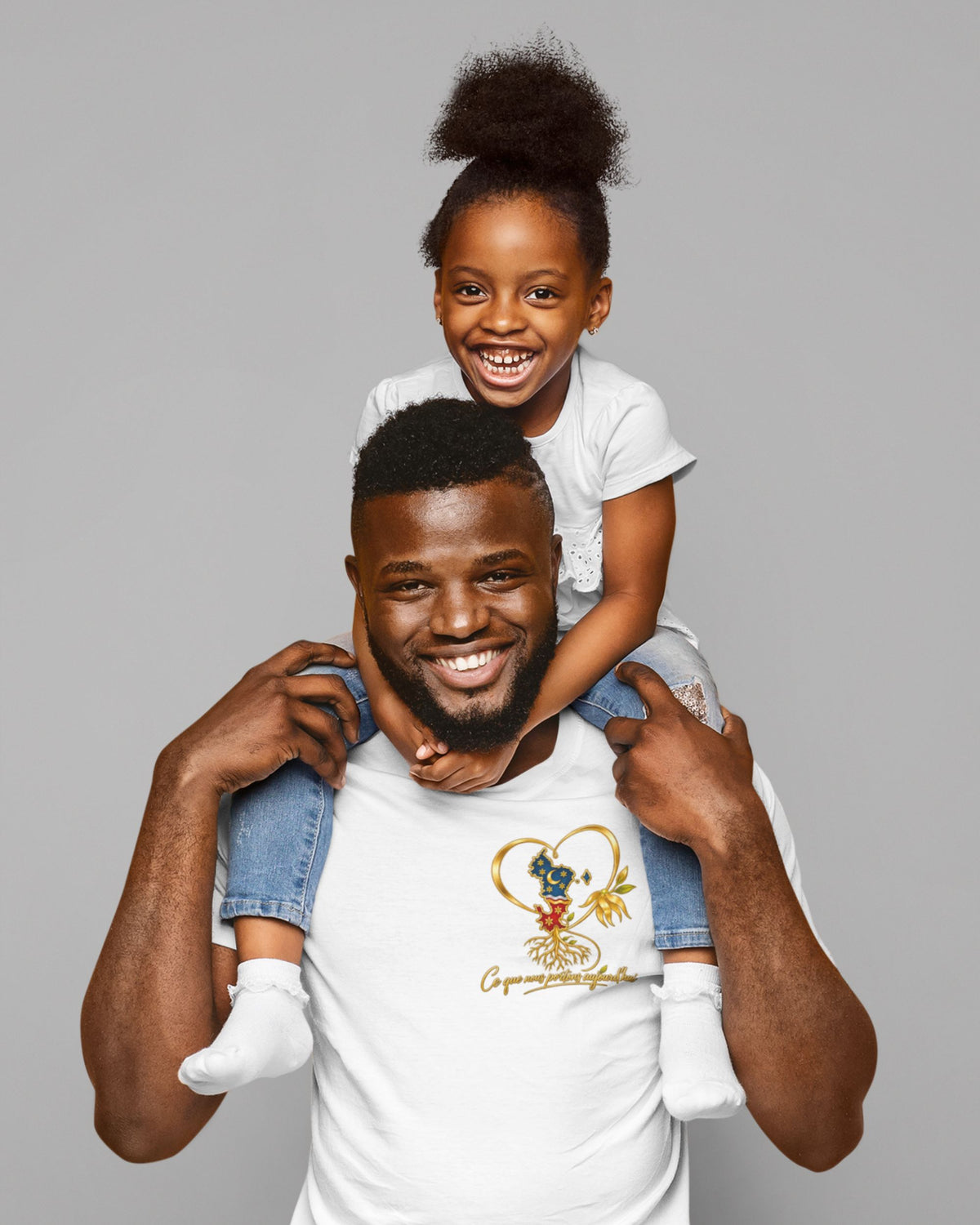  Homme portant le t-shirt blanc WASI au motif de cœur doré et de carte de Mayotte, avec une enfant souriante sur les épaules.