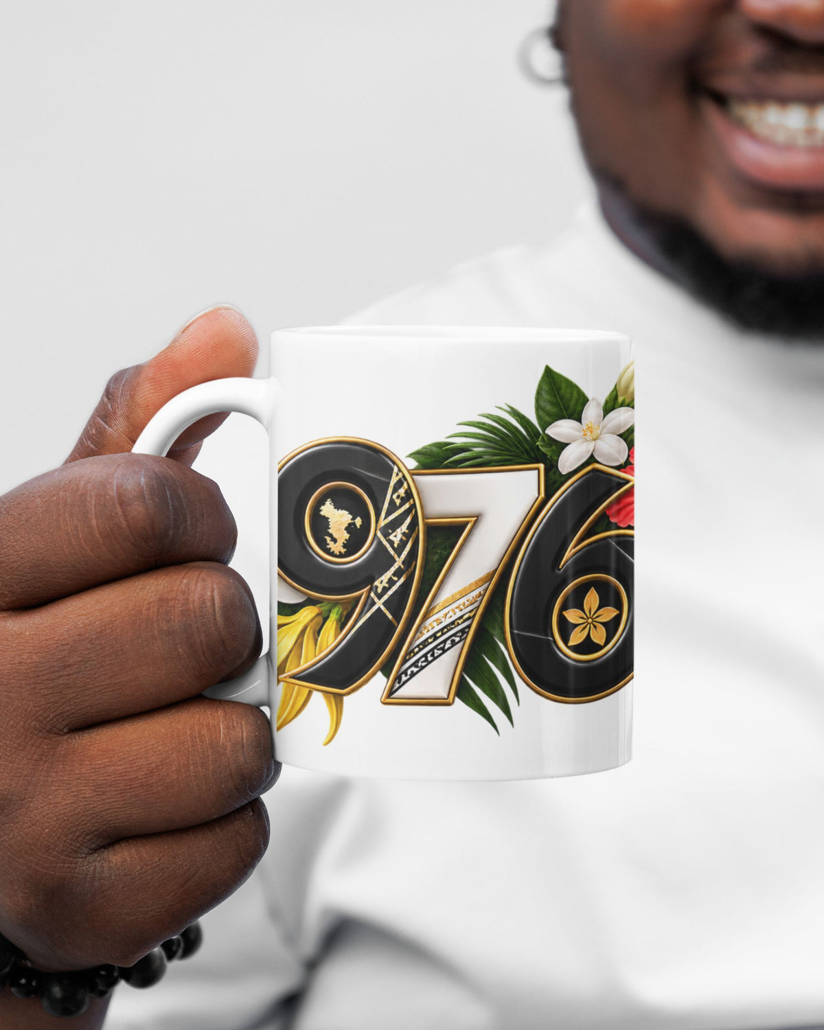 Homme tenant un mug blanc 976 Mayotte décoré de fleurs tropicales et de symboles mahorais, création WASI Maoré.
