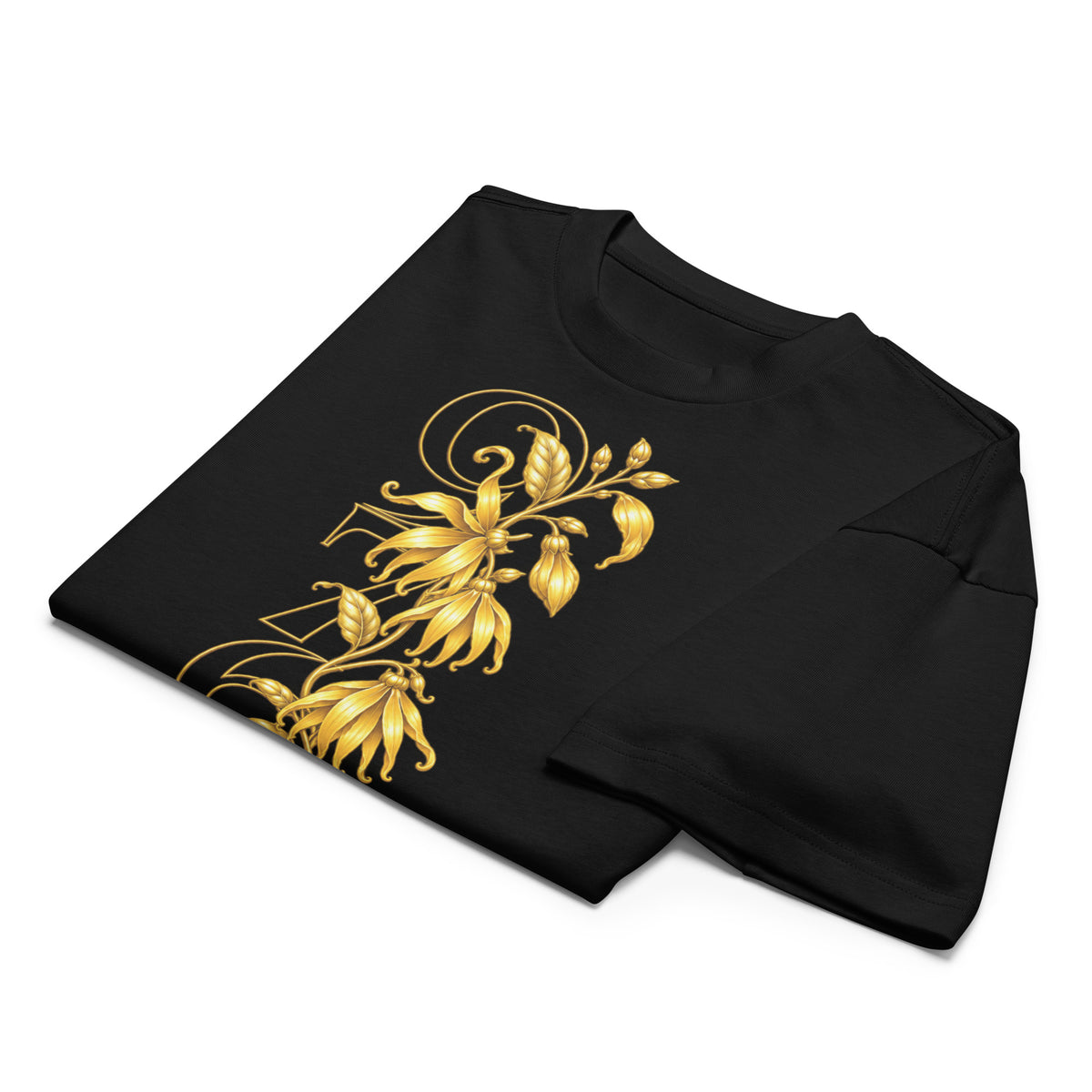 T-shirt noir YLANG — L’Or de Mayotte plié sur fond blanc, avec un détail du motif floral d’ylang-ylang doré.