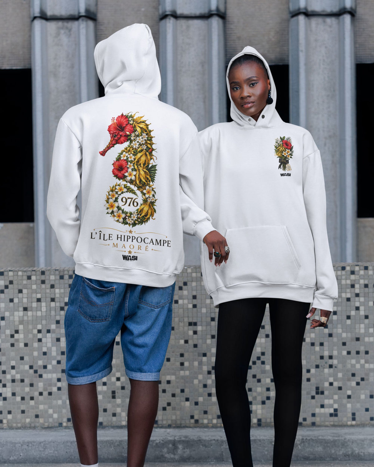 Deux personnes portant un sweat à capuche blanc WASI avec illustration florale sur la poitrine et grand hippocampe fleuri 976 au dos, vêtement streetwear unisexe inspiré de la biodiversité et du patrimoine de Mayotte.