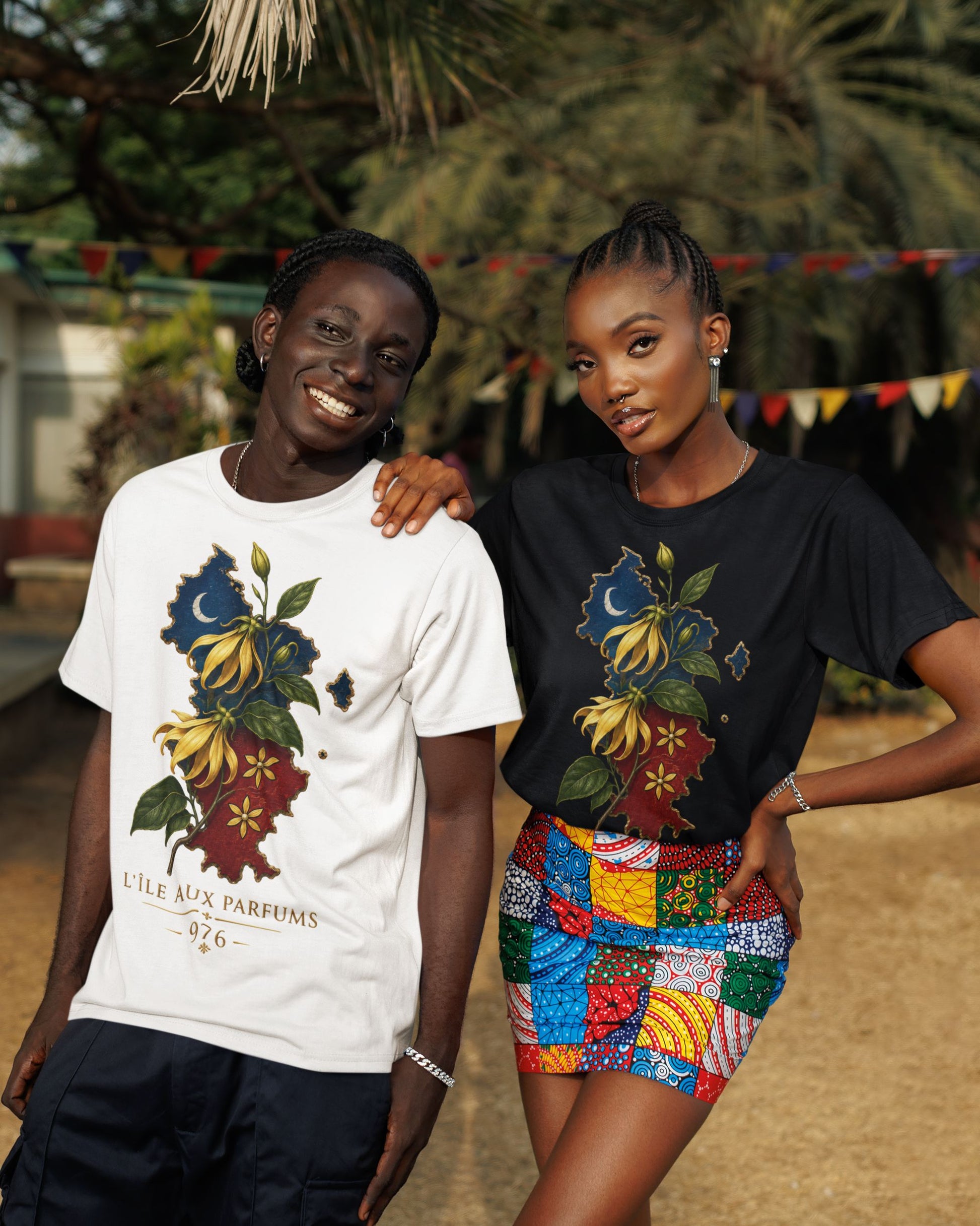 Deux personnes portant des t-shirts WASI L'Île aux Parfums 976 en coton, disponibles en blanc et noir, avec illustration de la carte de Mayotte et de fleurs d'ylang-ylang, photographie lifestyle en extérieur.