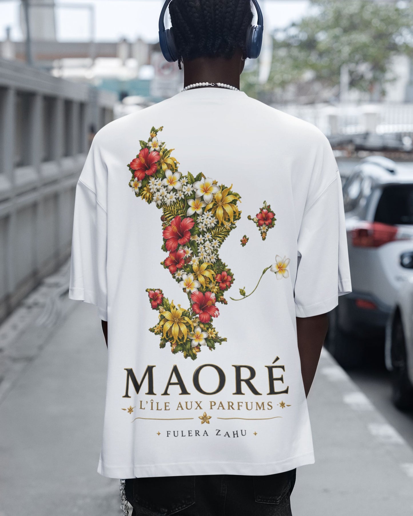 Vue de dos d'un t-shirt oversize blanc WASI avec une illustration florale représentant la carte de Mayotte et l'inscription « MAORÉ – L'ÎLE AUX PARFUMS », style streetwear unisexe.