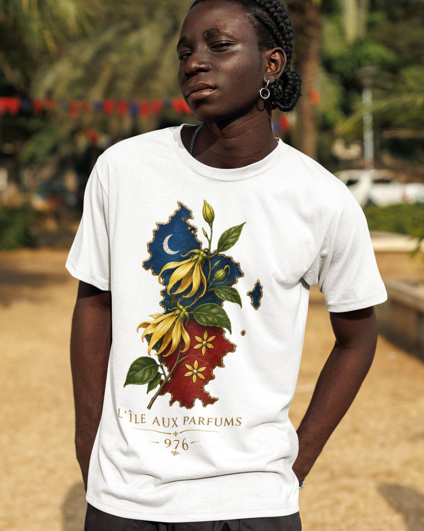Personne portant un t-shirt blanc WASI L'Île aux Parfums 976 en coton avec illustration de la carte de Mayotte, fleurs d'ylang-ylang et végétation tropicale, photographie lifestyle en extérieur.