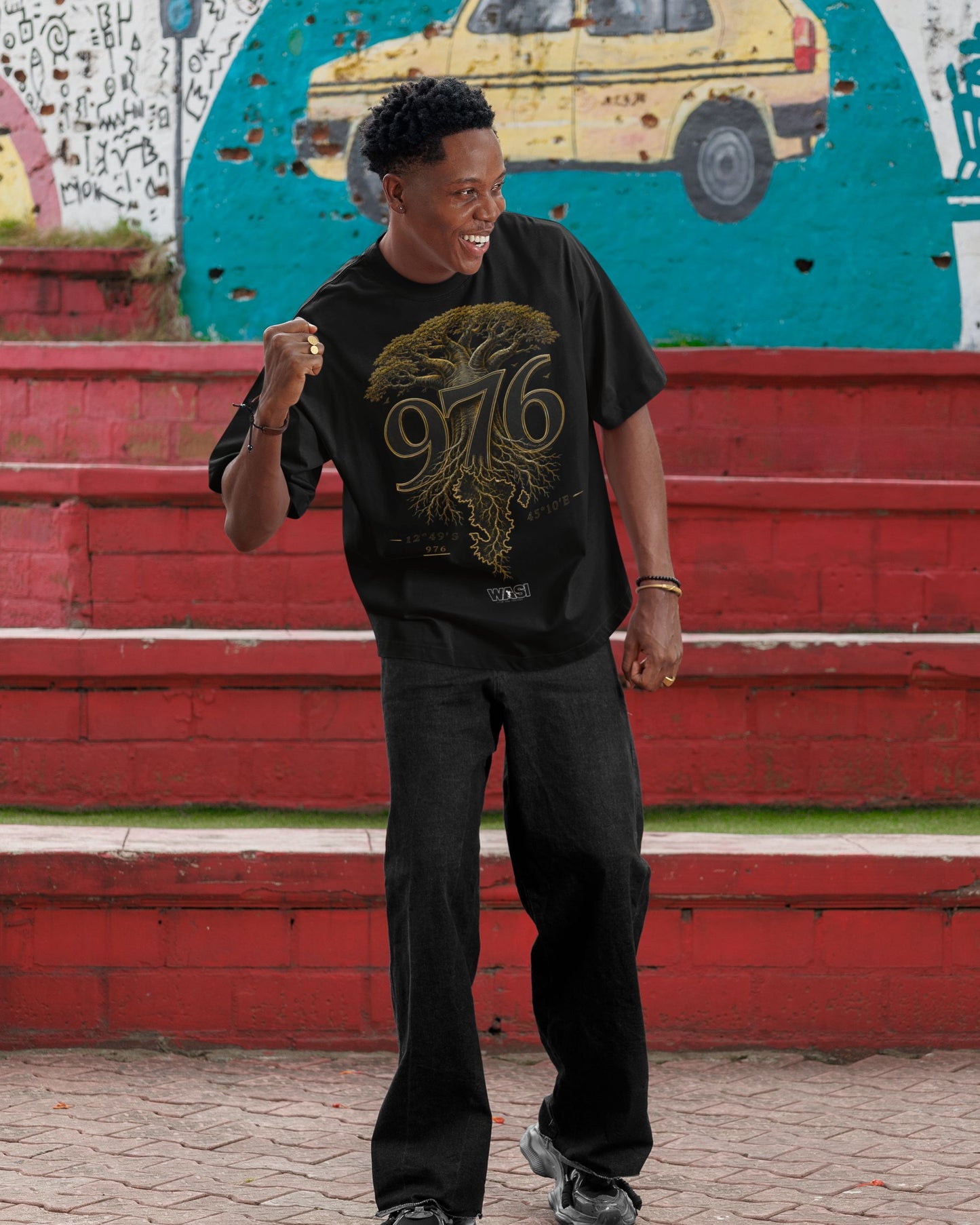 Homme portant un t-shirt oversize noir WASI avec le design 976 Baobab Roots inspiré du baobab de Mayotte, photographie lifestyle streetwear en extérieur.